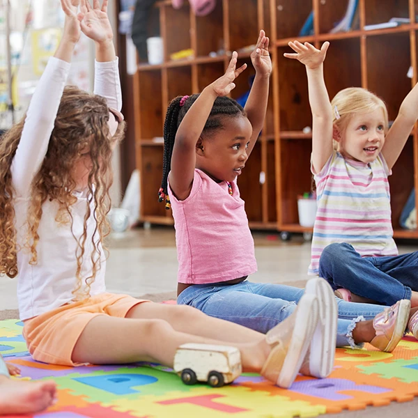 Preschool for Four Year Olds - Northern Virginia Academy of Early Learning - group of children with arms raised interacting with teacher